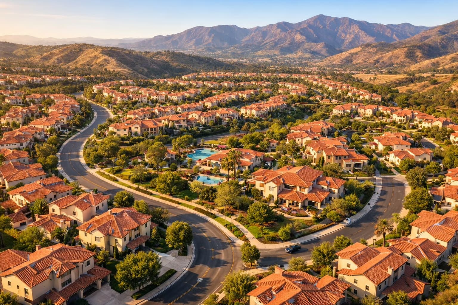 Aerial view of tile-roofed neighborhoods and winding streets with the Saddleback foothills behind