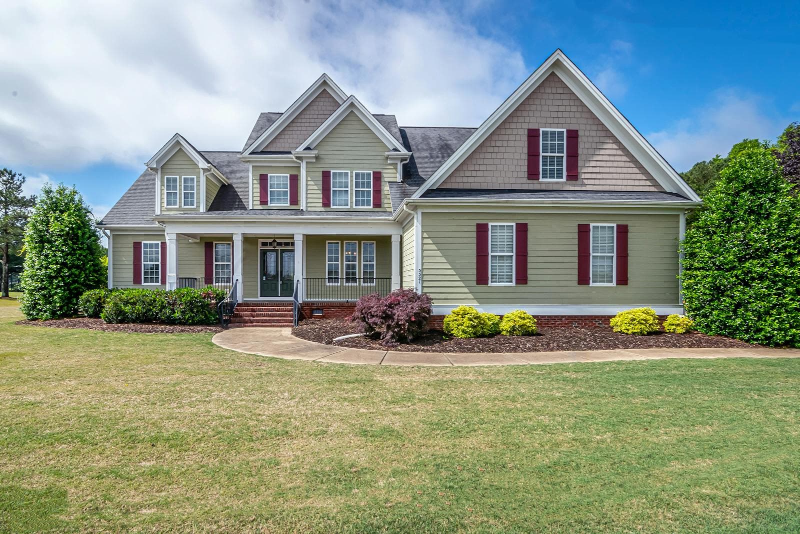Two-story suburban family home with a manicured lawn and front porch